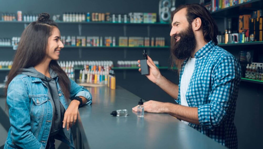 Seorang gadis mendengar jurujual di kedai rokok untuk memperkenalkannya tentang cara memilih peranti vape yang baik